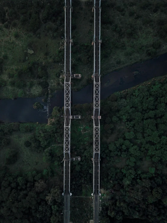 an aerial view of a bridge in the middle of a forest, not train tracks, on a dark background, powerlines, 🦑 design