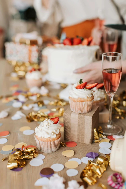 a table topped with cupcakes and a glass of wine, pexels contest winner, happening, confetti, orange and white color scheme, gifts, long table