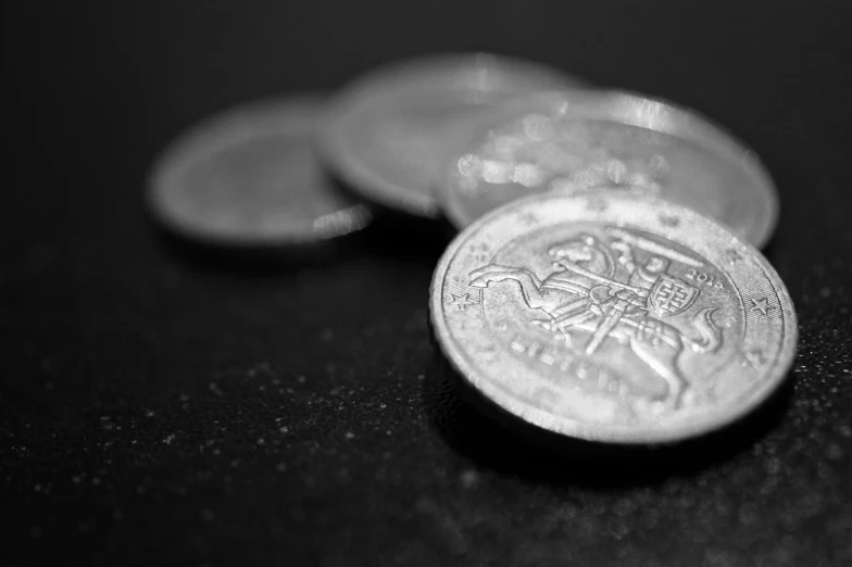 a bunch of coins sitting on top of a table, a black and white photo, by Daniel Lieske, gleaming silver, blur focus, ilustration, close-up product photo