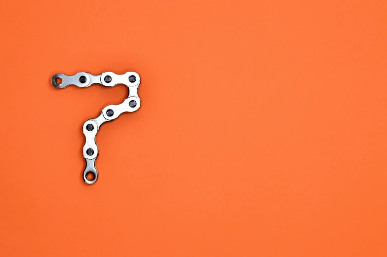 a bicycle chain on an orange background, by Werner Gutzeit, trending on pexels, precisionism, question marks, seven, on grey background, robotic arm