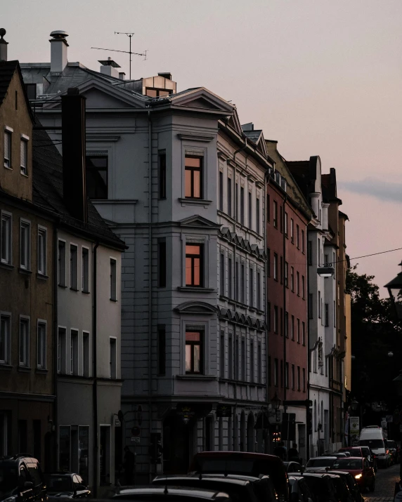 a group of cars driving down a street next to tall buildings, pexels contest winner, german romanticism, calm evening, white houses, kreuzberg, photo of a beautiful window