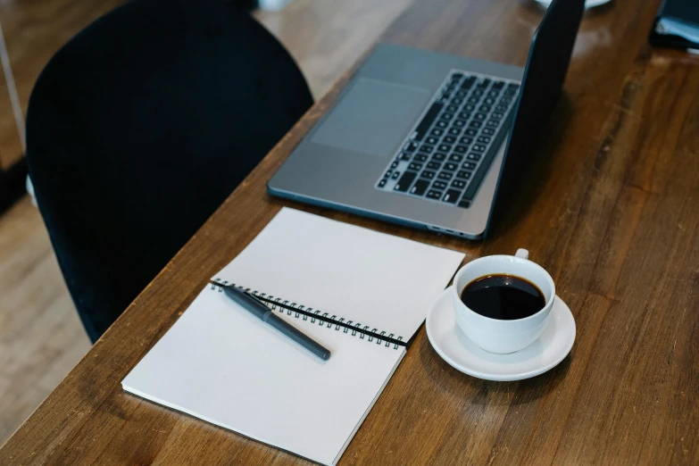 a laptop computer sitting on top of a wooden desk next to a cup of coffee, a drawing, pexels contest winner, pen and paper, 9 9 designs, black, round format