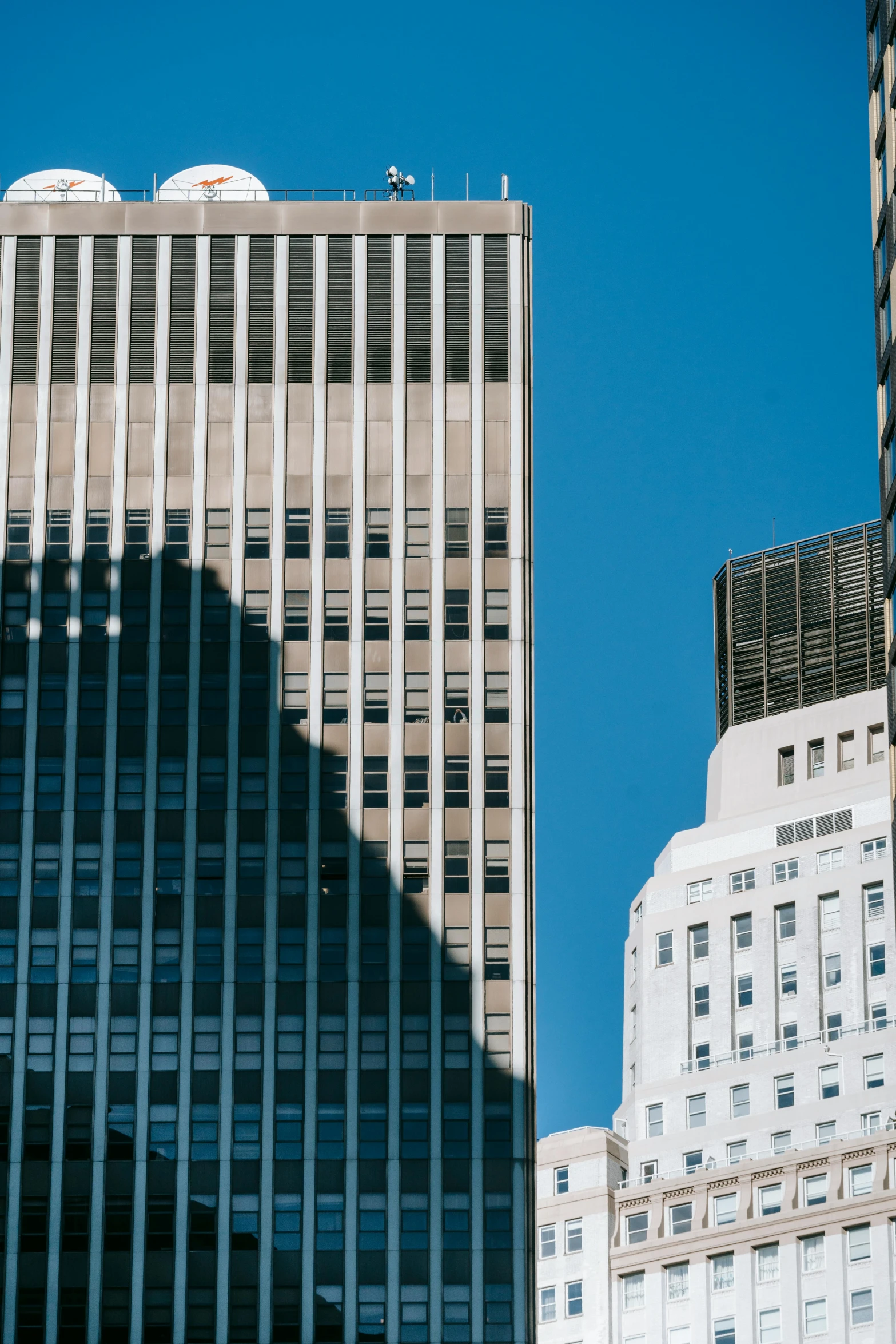 a couple of tall buildings sitting next to each other, inspired by Vivian Maier, trending on unsplash, directional sunlight skewed shot, zoomed in shots, wall street, exterior photo