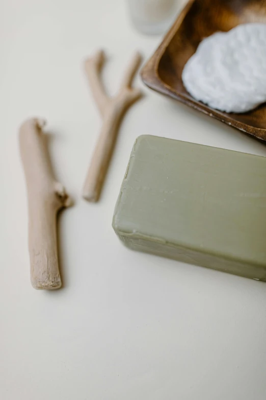 a couple of soap bars sitting on top of a table, inspired by Ceferí Olivé, unsplash, renaissance, olive green, holding a wood piece, exposed bone, thumbnail