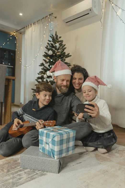 a family sitting on the floor in front of a christmas tree, looking at his phone, profile image, thumbnail, gen z