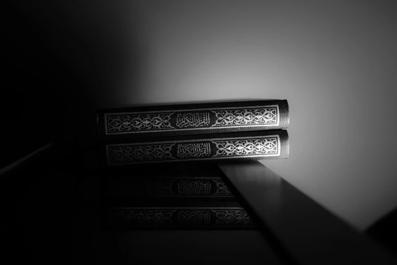 a couple of books sitting on top of a table, a black and white photo, hurufiyya, detailed high contrast lighting, profile picture 1024px, arabic, hdr photo