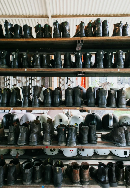 a bunch of shoes that are on a shelf, unsplash, firefighting gear, black iron suit of armour, in a workshop, worksafe. instagram photo
