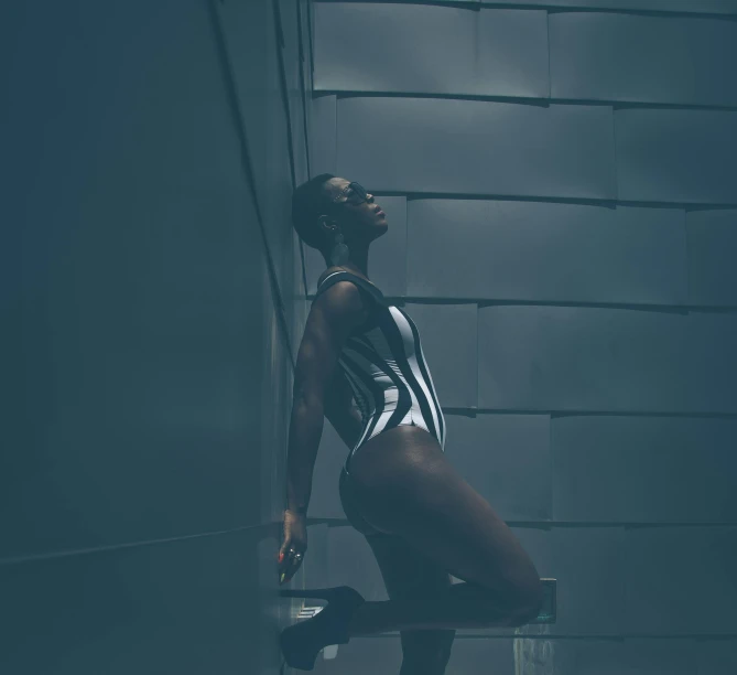 a woman in a bathing suit leaning against a wall, unsplash, afrofuturism, in a dark futuristic room, maria borges, high key lighting, wearing leotard