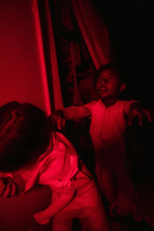 a couple of kids standing next to each other in a room, an album cover, inspired by Carrie Mae Weems, pexels, symbolism, blood aura red light, screaming at the camera, low quality photo, yeezus