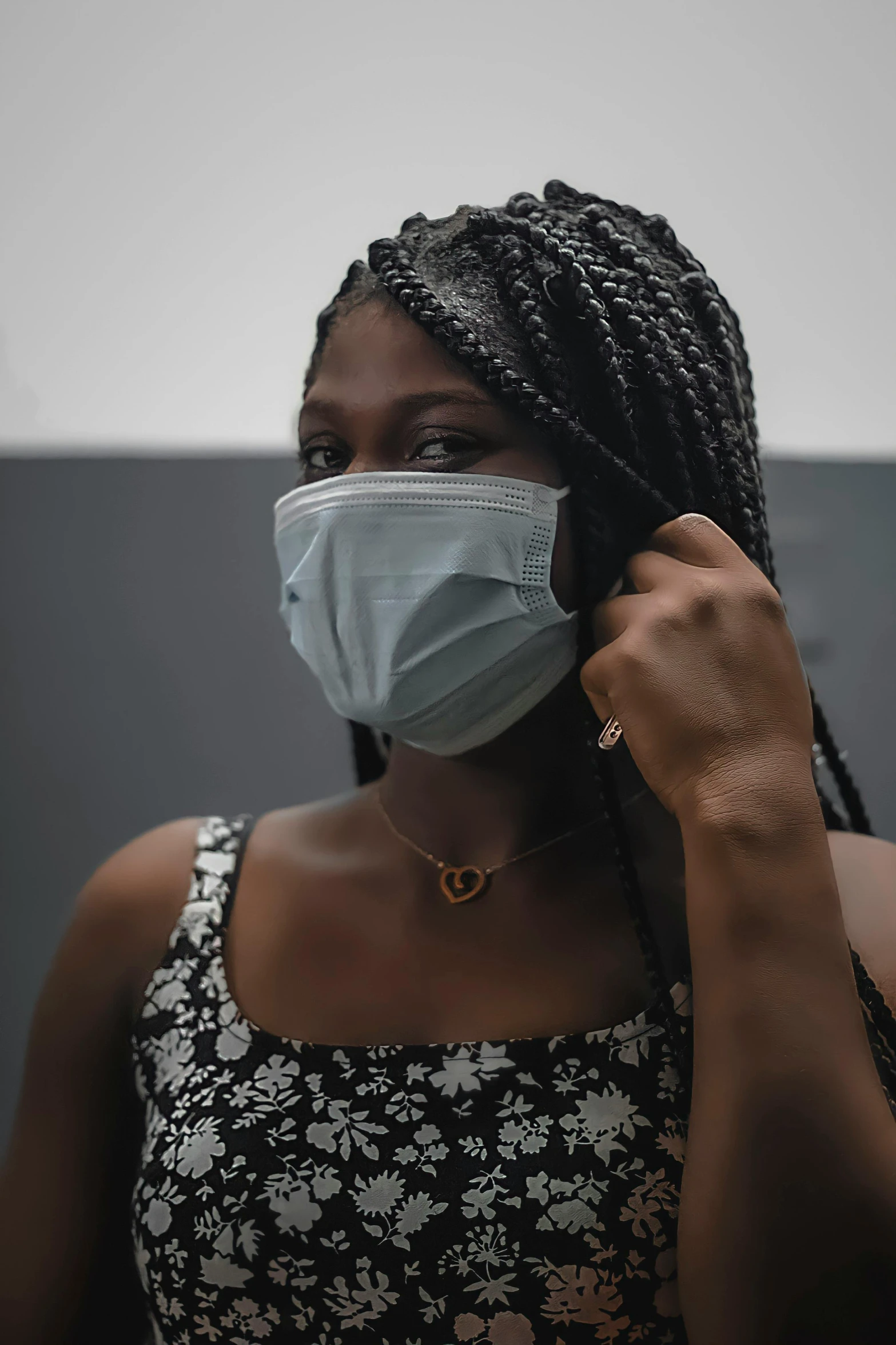 a woman wearing a face mask while talking on a cell phone, by Carey Morris, trending on pexels, afrofuturism, on grey background, wearing bra, surgical mask covering mouth, pictured from the shoulders up