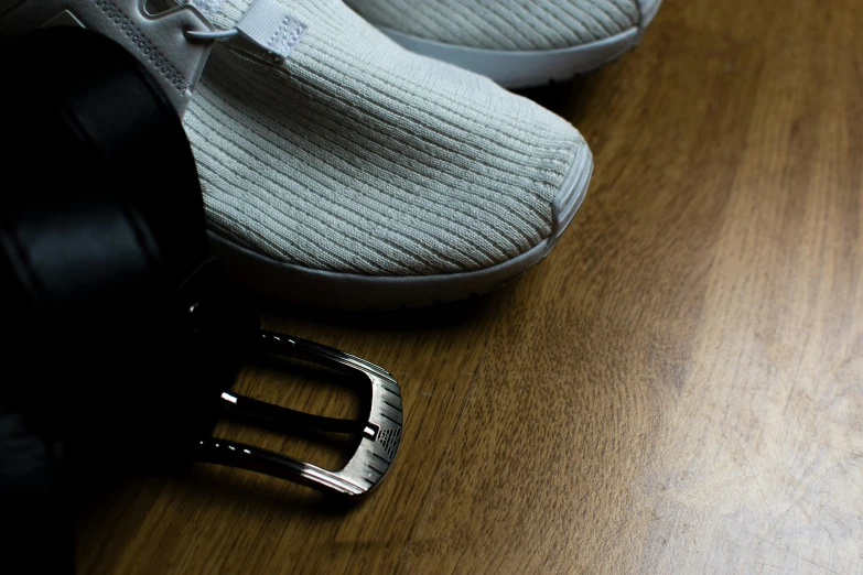 a pair of shoes and a belt on a wooden floor, unsplash, white biomechanicaldetails, corduroy, platinum, 33mm photo