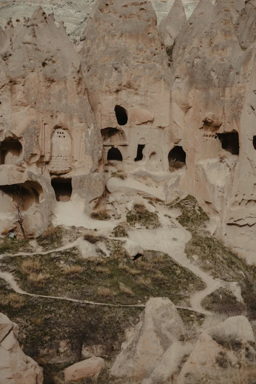 a group of cave houses built into the side of a mountain, by Muggur, stone carvings, zoomed out shot, 8 x, multiple stories