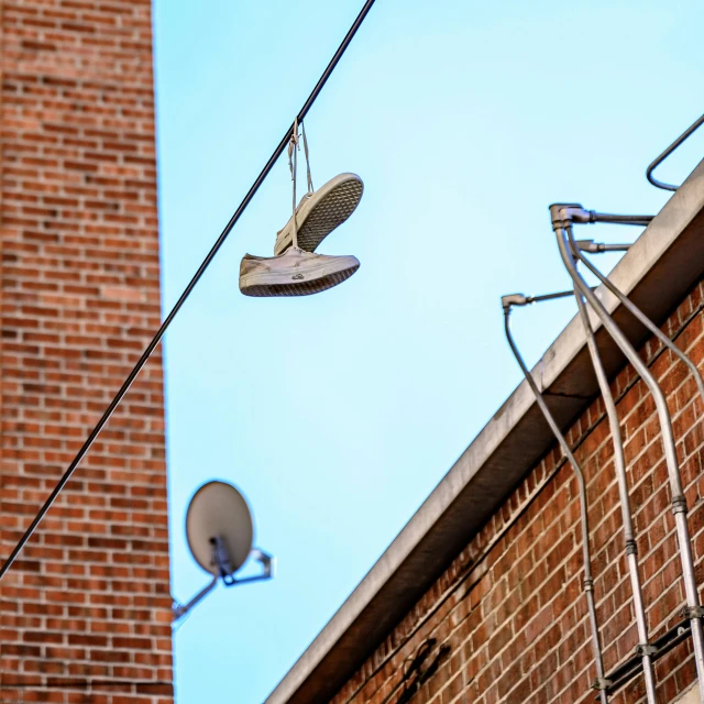 a pair of shoes hanging off the side of a building, by Mike Bierek, pexels contest winner, satellite dishes, wires and lights, alleys, sunny day time