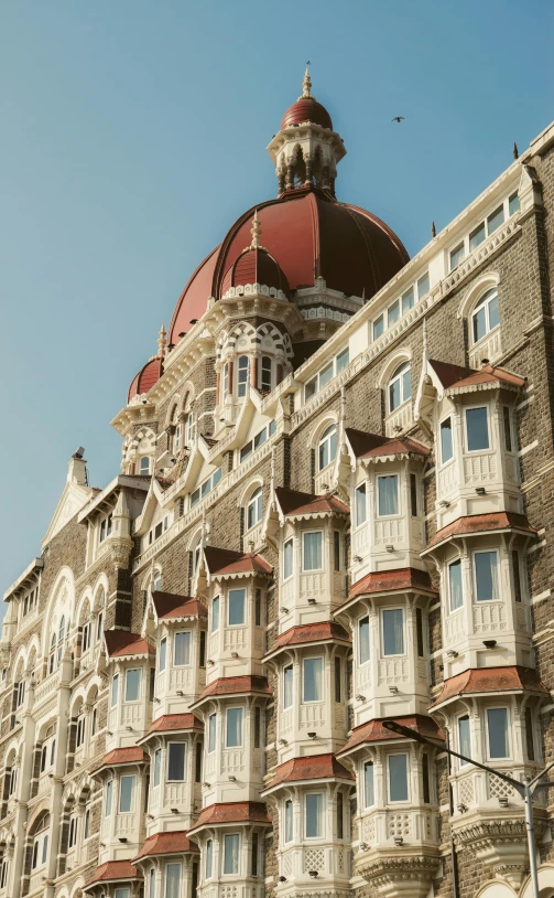 a tall building with a red dome on top of it, inspired by Jitish Kallat, art nouveau, half length shot, hotel, coastline, queen victoria