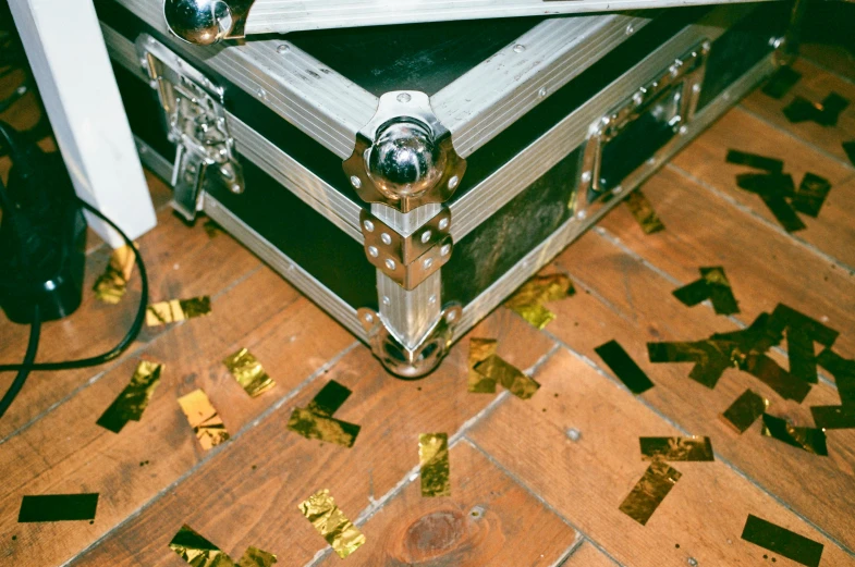 a suitcase sitting on top of a wooden floor covered in confetti, by Julia Pishtar, happening, gold trimmings, concert, pristine marble trunk, 35 mm photo