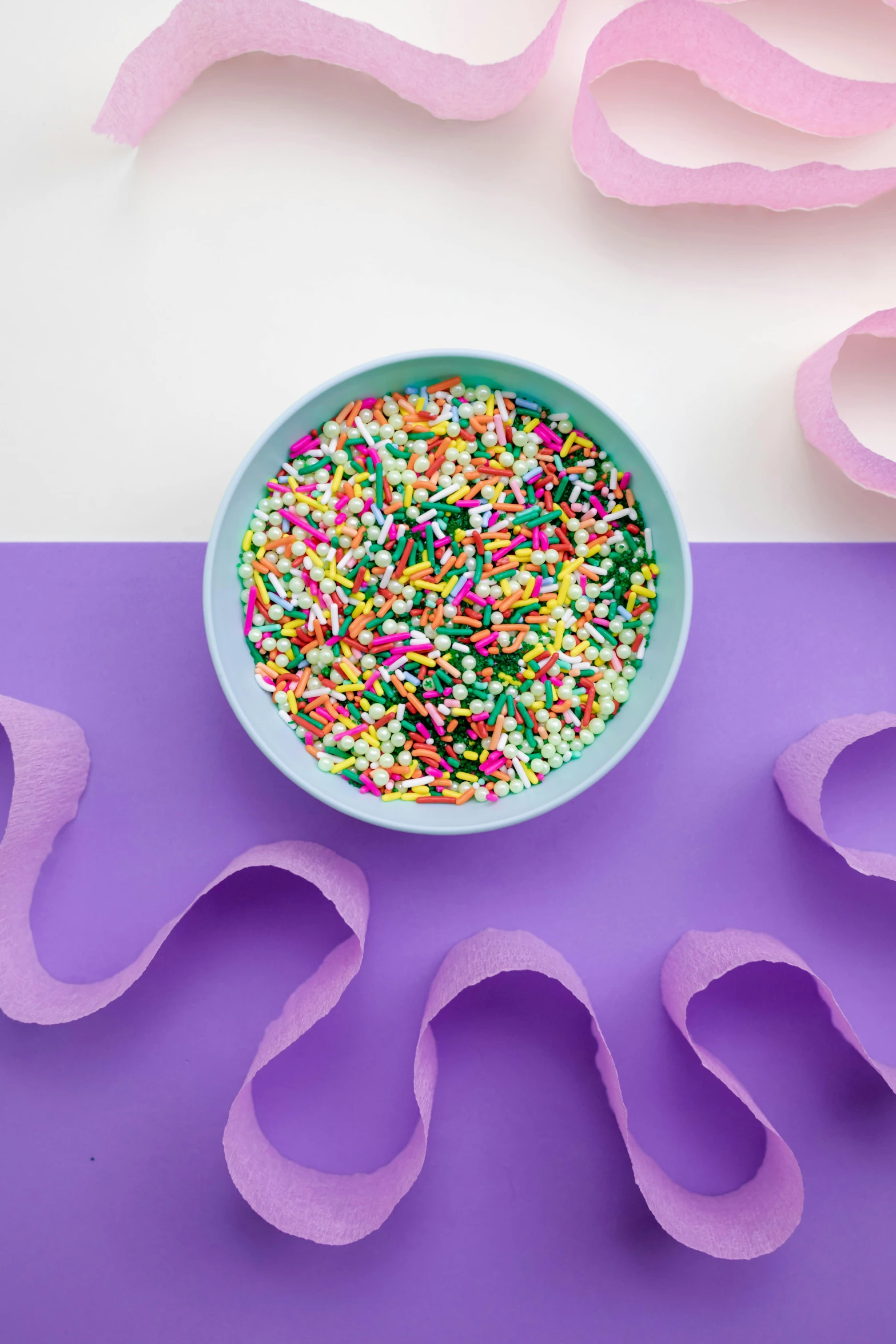 a bowl filled with sprinkles on top of a purple and white table, a picture, trending on pexels, wide ribbons, bright vivid color hues:1, detailed product image, detail shot
