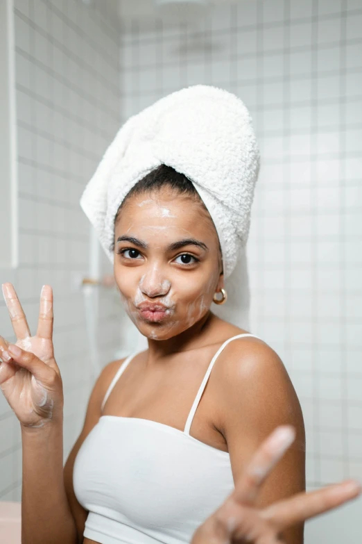 a woman with a towel on her head making a peace sign, trending on pexels, happening, square face, showers, with brown skin, 7
