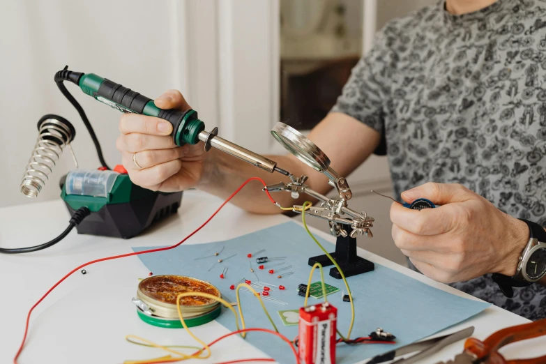 a person using a soldering machine on a table, pexels, fan favorite, hilarious, album art, featuring wires