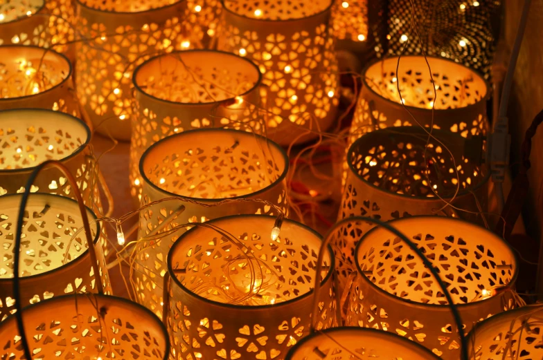 a group of lit candles sitting on top of a table, yellow lanterns, soft and intricate, light particules, glowing heating coils