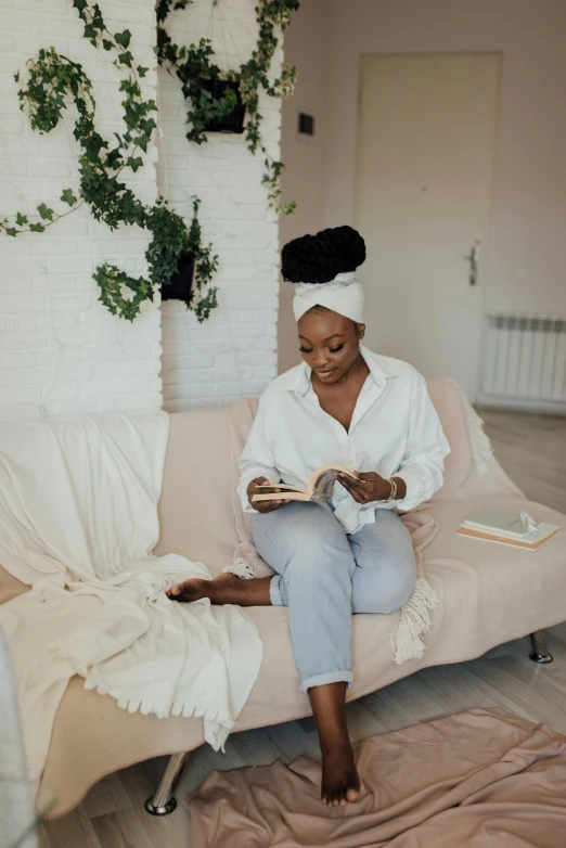 a woman sitting on a couch reading a book, by Dulah Marie Evans, topknot, white shirt and jeans, calm environment, black woman