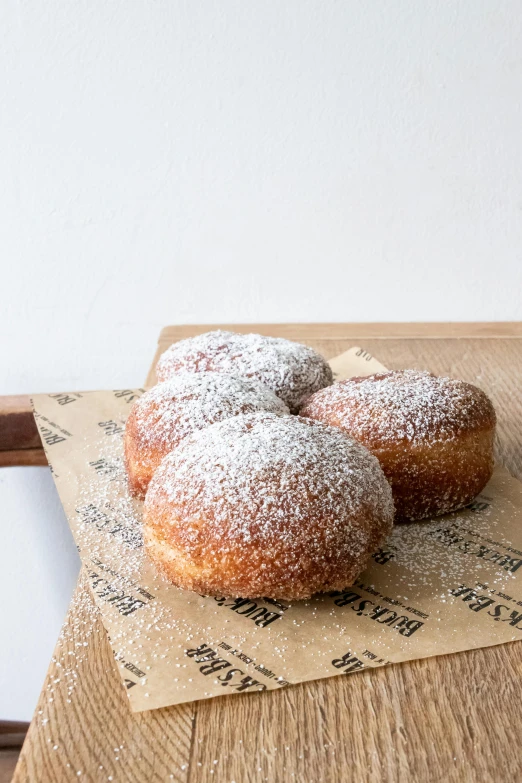 a wooden table topped with three donuts covered in powdered sugar, by Tom Bonson, baroque, buzzed sides, high grain, award - winning, sleek hands