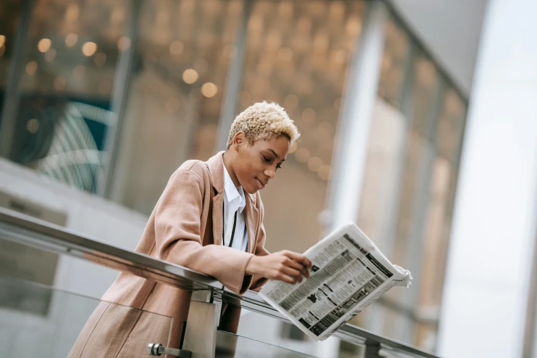 a woman reading a newspaper while standing on a railing, trending on pexels, private press, short blonde afro, wearing a light - pink suit, trench coat and suit, justify content center