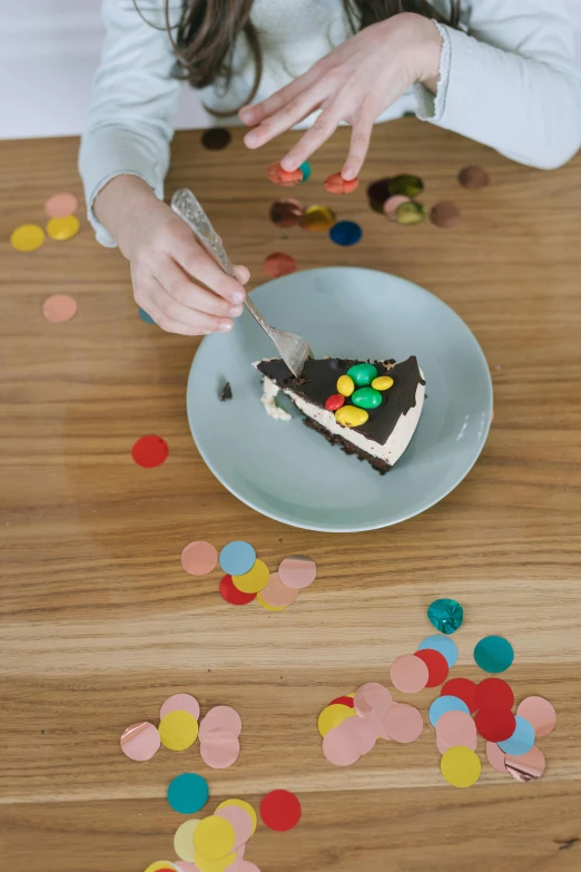 a little girl sitting at a table with a piece of cake, pexels contest winner, confetti, served on a plate, brown, minimalist