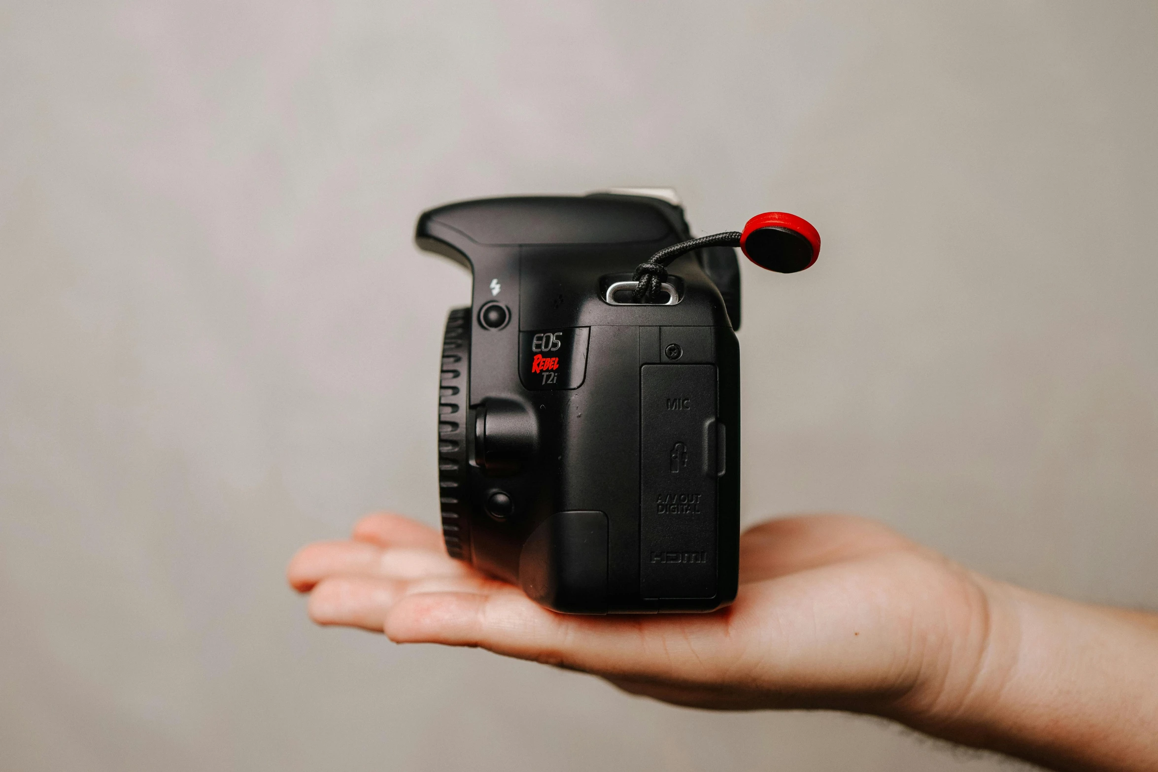 a person holding a camera in their hand, black steel with red trim, right hand side profile, high quality product image”, unsplash photography