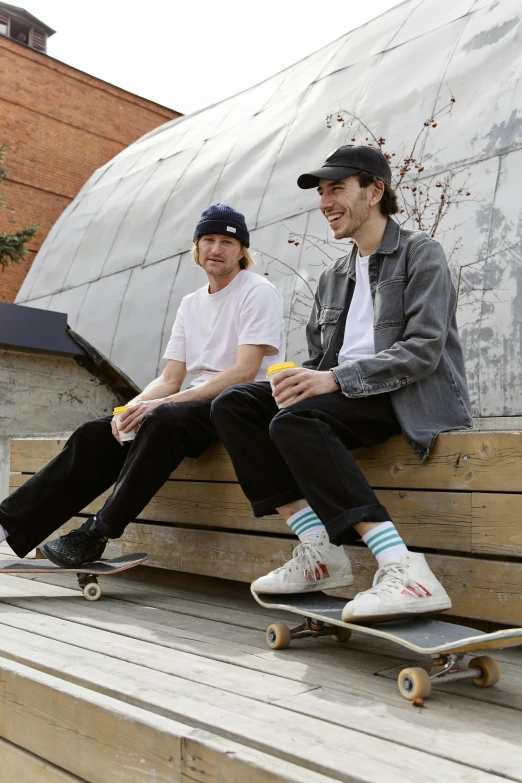 a couple of men sitting on top of a wooden bench, a portrait, by Lee Gatch, unsplash, realism, riding a skateboard, bradley james and colin morgan, snacks, wearing a baseball cap backwards