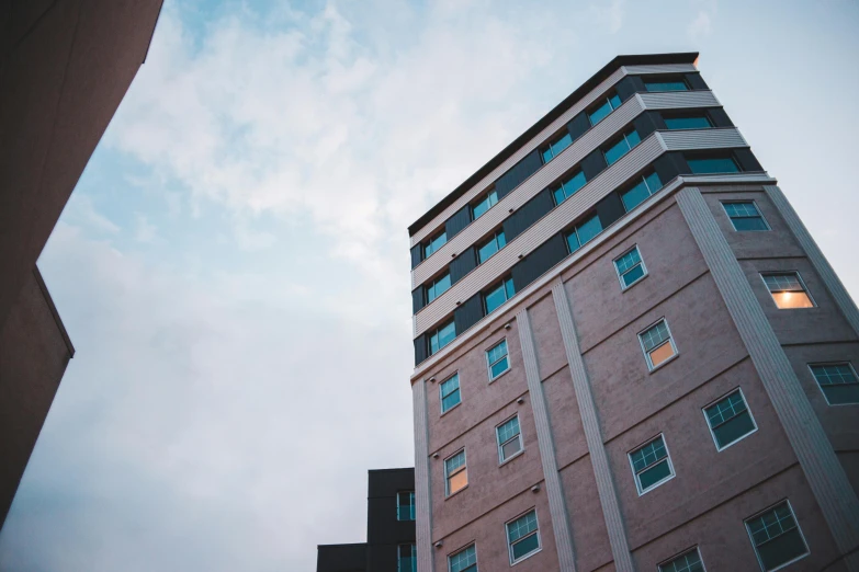 a tall building sitting in the middle of a city, a photo, unsplash, modernism, hospital, ten flats, brown, low-angle