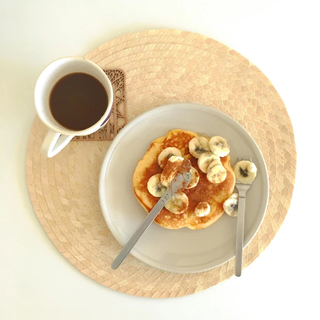 a plate topped with pancakes and bananas next to a cup of coffee, pexels contest winner, hurufiyya, high angle view, gif, at home, studio photo