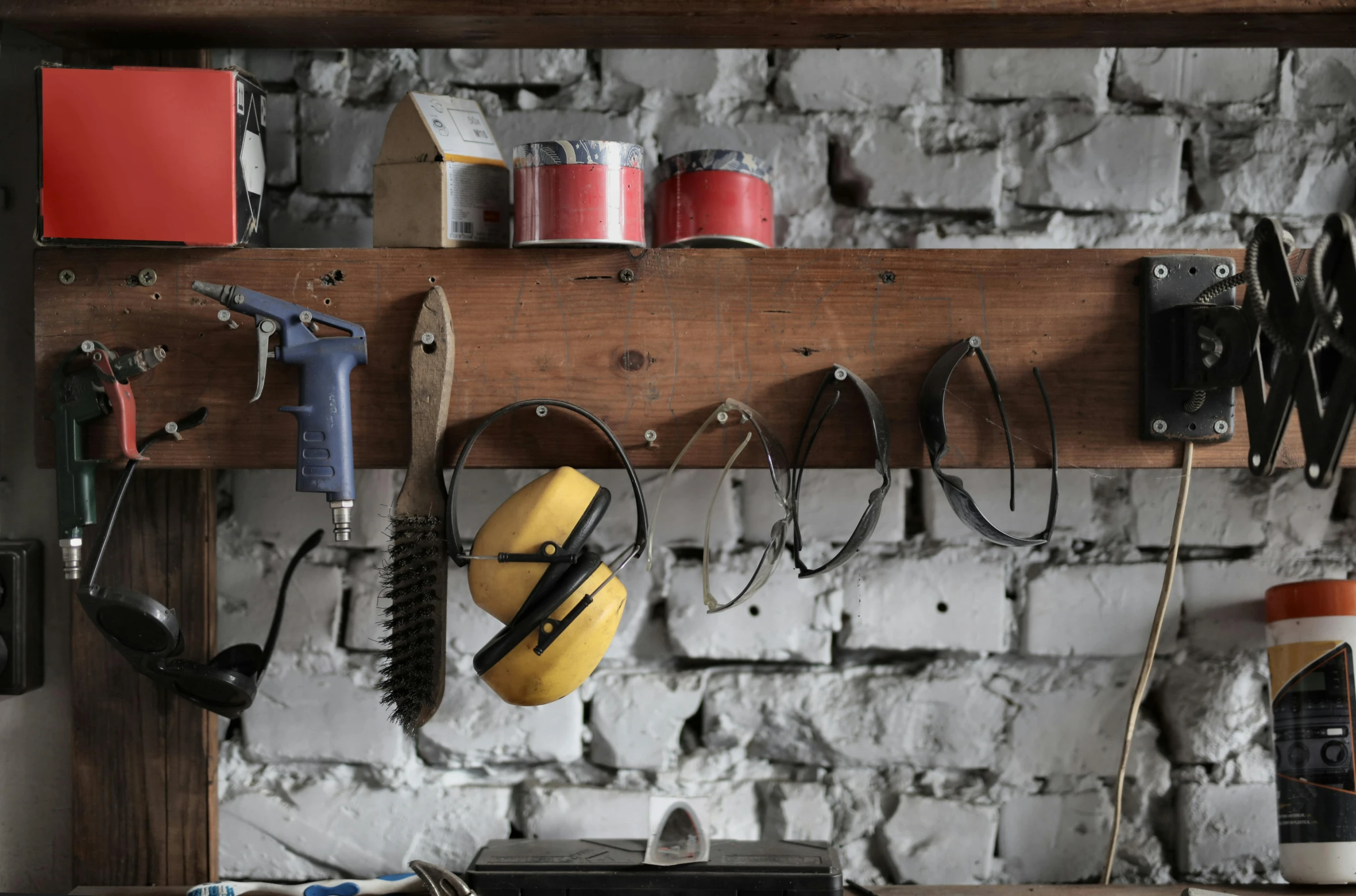 a bunch of tools are hanging on a wall, a portrait, pexels, jar on a shelf, charcoal and yellow leather, grungy, brick