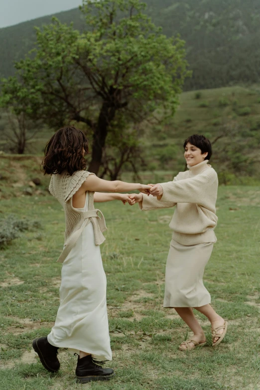 a couple of people that are standing in the grass, an album cover, by Marina Abramović, unsplash, renaissance, girl in white dress dancing, lesbians, chile, holding hands