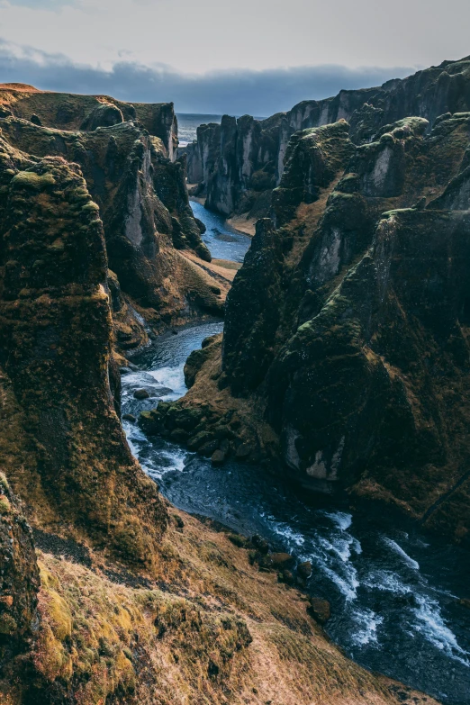 a man standing on top of a cliff next to a river, by Johannes Voss, pexels contest winner, renaissance, icelandic valley, high view, majestic spires, fine art print