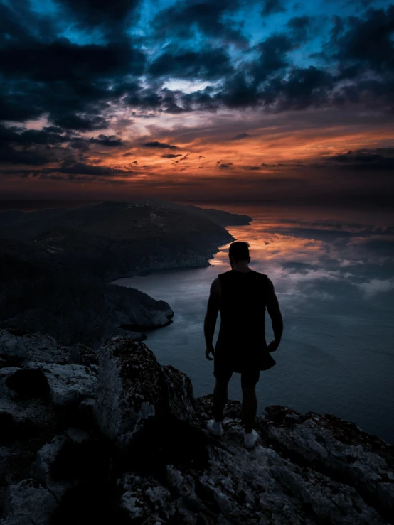 a man standing on top of a mountain at sunset, by Sebastian Spreng, pexels contest winner, the sea and storms behind him, dark. no text, profile picture, (night)