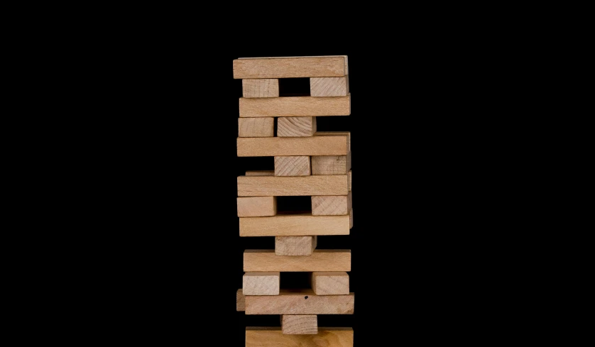 a stack of wooden blocks sitting on top of a table, on a black background, twister, medium, image