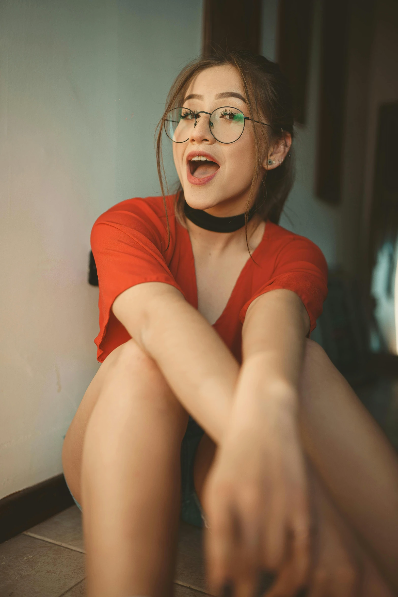 a woman with glasses sitting on the floor, trending on pexels, wearing red shorts, wide open mouth, sexy :8, gif