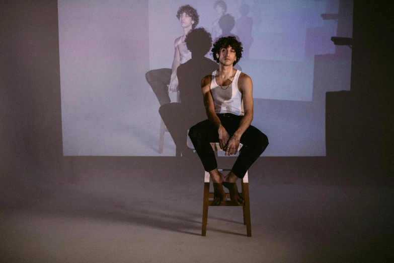 a woman sitting on top of a wooden chair, inspired by Nan Goldin, unsplash, video art, finn wolfhard, performing a music video, robert sheehan, imaan hammam