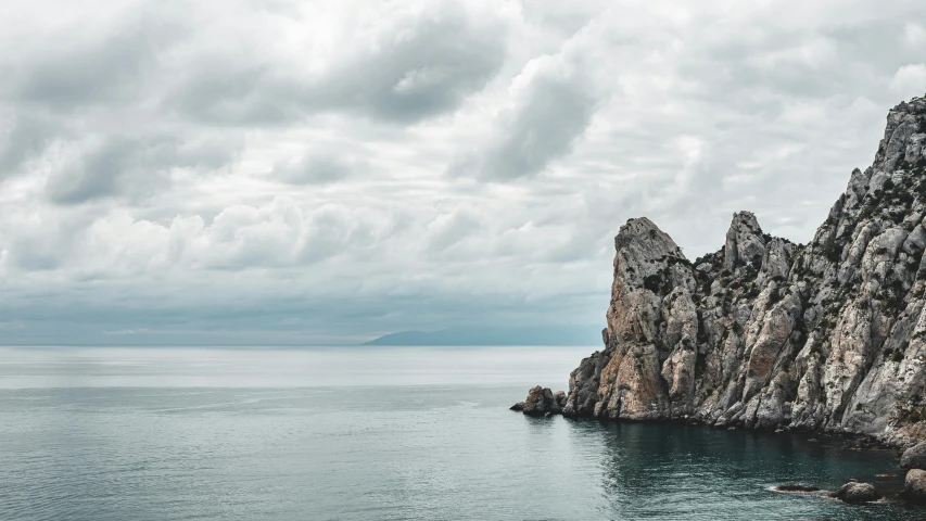 a rock formation in the middle of a body of water, a photo, unsplash contest winner, romanticism, overcast gray skies, near lake baikal, mediterranean vista, conde nast traveler photo