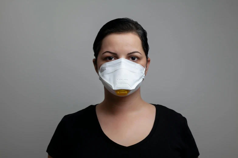 a woman in a black shirt is wearing a face mask, on grey background, worksafe.2000s, yellow, with a pointed chin