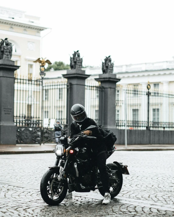 a man riding a motorcycle down a cobblestone street, pexels contest winner, neoclassicism, dressed in black body armour, profile image, moscow, non-binary