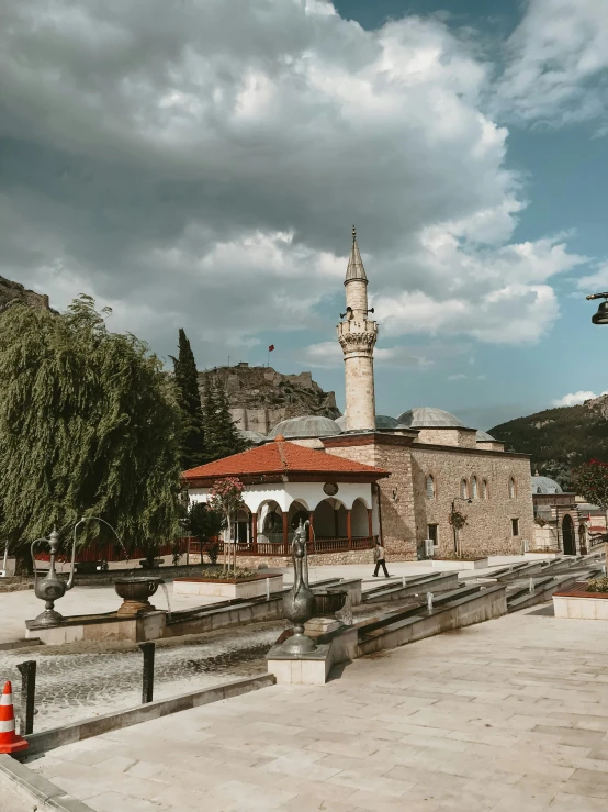 a clock tower sitting in the middle of a town, by Ibrahim Kodra, pexels contest winner, hurufiyya, mountain in the background, fountains and arches, he is in a mosque, bosnian