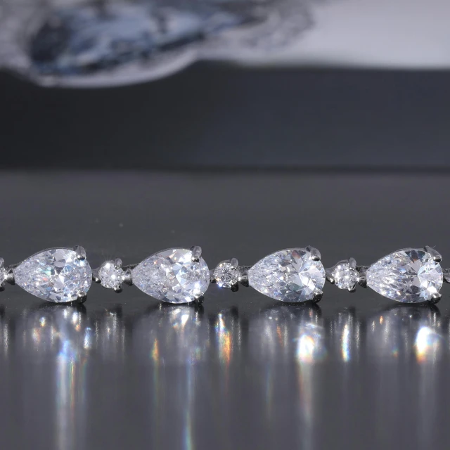 a row of five pear shaped diamonds on a table, hurufiyya, silver color, h 1 0 8 0