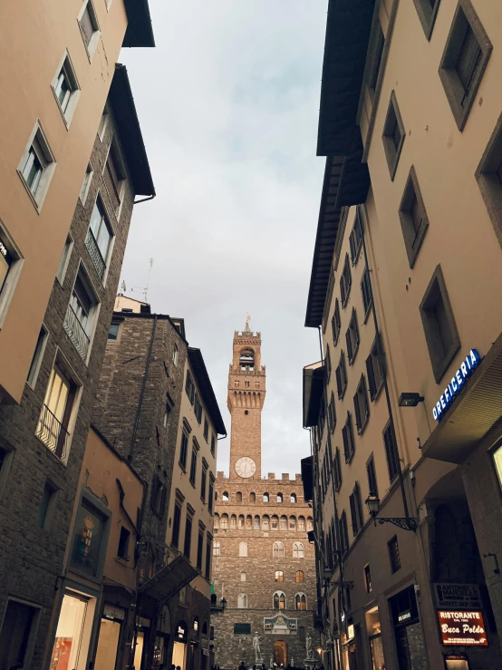 a narrow street with a clock tower in the background, an album cover, inspired by Eliseu Visconti, pexels contest winner, renaissance, bargello, overlooking, to