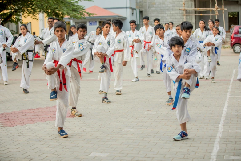 a group of young men standing next to each other, by Daryush Shokof, pexels contest winner, danube school, doing martial arts, school courtyard, white uniform, red and blue garments