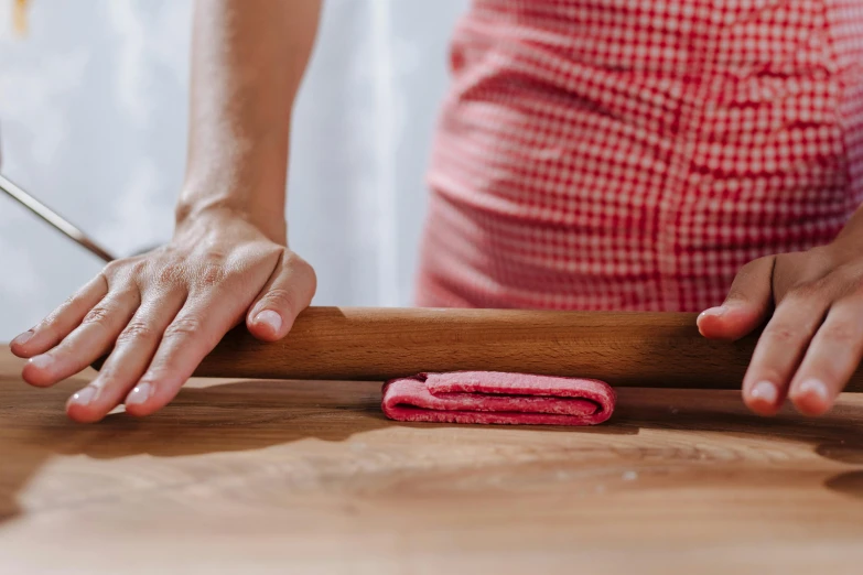 a woman rolling out dough on a wooden table, by Julia Pishtar, trending on pexels, long trunk holding a wand, clean detail, maintenance, thumbnail