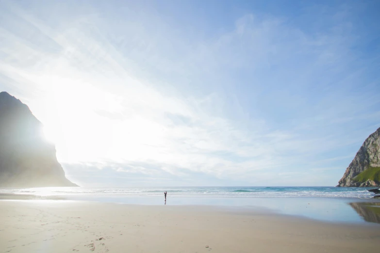 a person standing on a beach next to the ocean, marsden, beaches, big sky, brightly lit