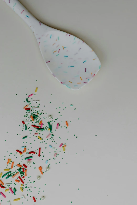 a spoon and some sprinkles on a table, inspired by Howardena Pindell, trending on unsplash, conceptual art, paper airplane, shattered wall, balloon, 15081959 21121991 01012000 4k