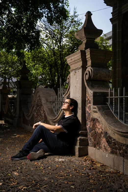 a man sitting on the ground in front of a gate, inspired by Albert Paris Gütersloh, unsplash, giant grave structures, well shaded, thoughtful pose, around 1 9 years old