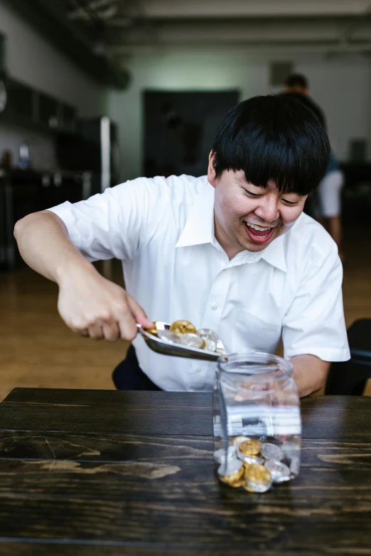 a man sitting at a table with a plate of food, spit flying from mouth, taejune kim, with a happy expression, bending down slightly